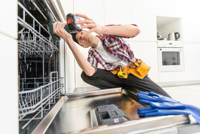 Person repairing dishwasher with drill